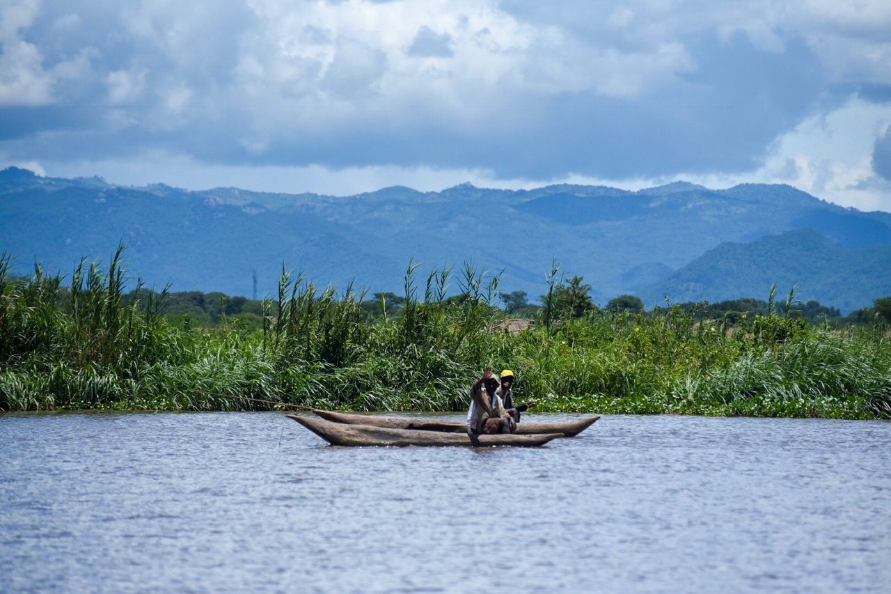 Fishermen in a dugout canoe passing the reeds